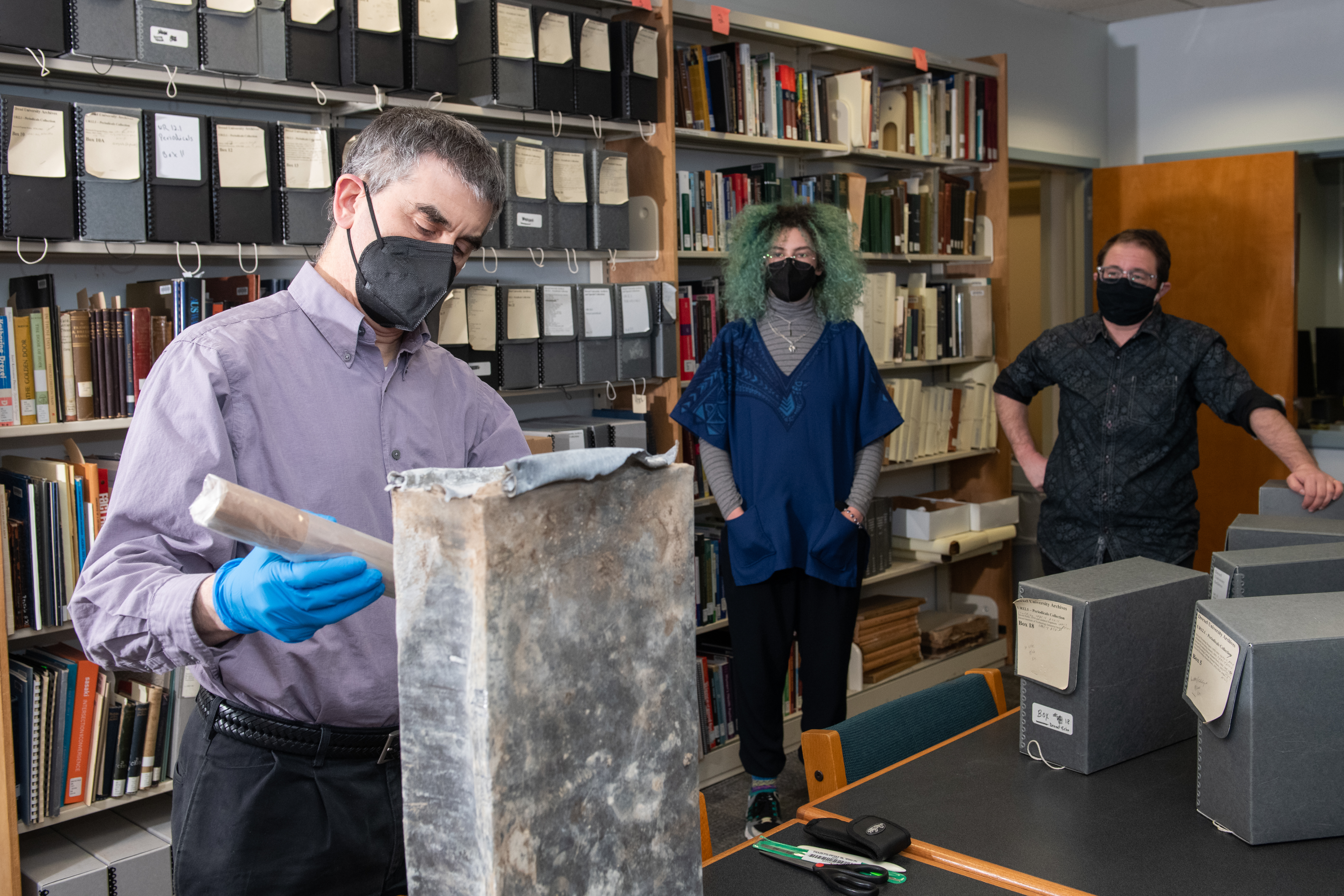 University Archives staff open the time capsule. From left to right: Archivist Matthew Lyons, former Archives Co-Op Hanna Pistorius, and Archivist Simon Ragovin